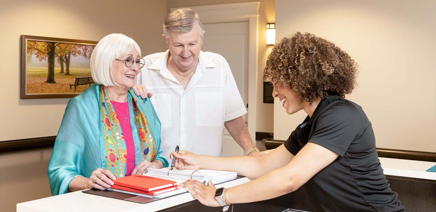 Elderly couple talking to a senior living community receptionist